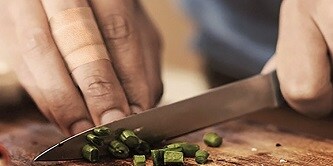 homme découpant de la ciboulette sur une planche
